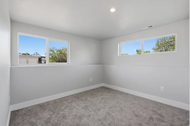 Room featuring light gray walls, white trim, gray carpet, and two egress windows