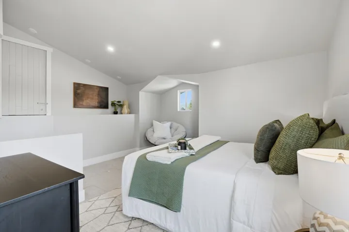 Attic bedroom featuring vaulted ceilings with recessed lighting, a built-in privacy wall, and a window providing natural light