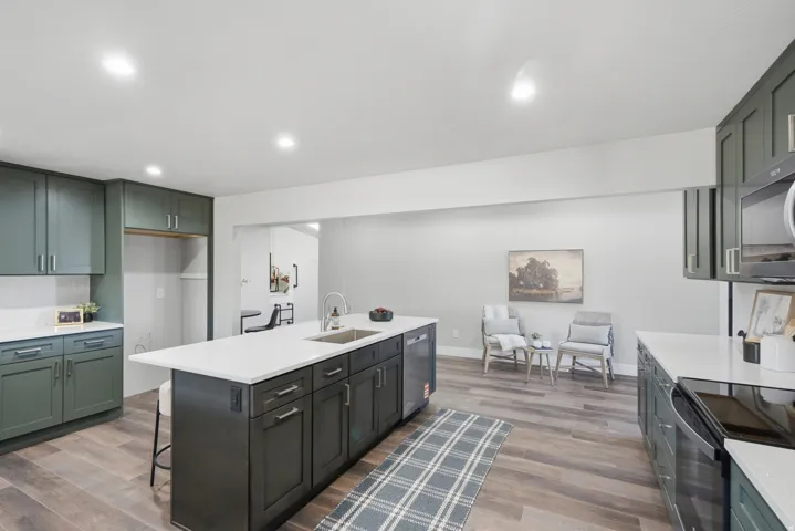 Contemporary kitchen featuring an expansive center island with an integrated sink and dishwasher, complemented by sleek white countertops