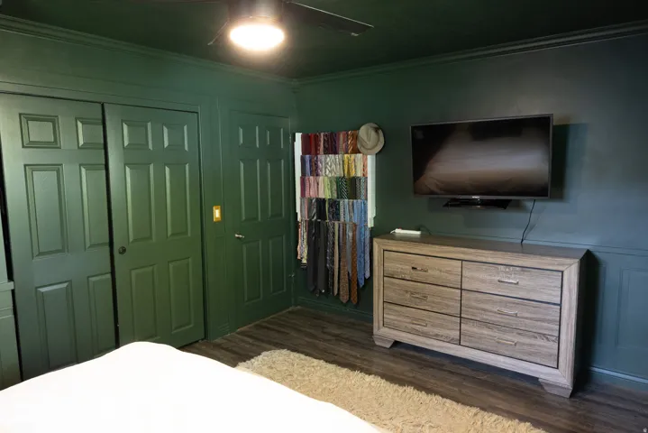 Interior space featuring wood-finish flooring, paneled walls, and a ceiling fan with integrated lighting