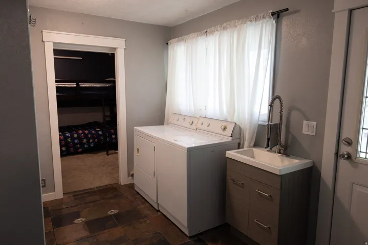 Laundry area featuring slate-look tile flooring, a utility sink with a modern faucet, and a large window