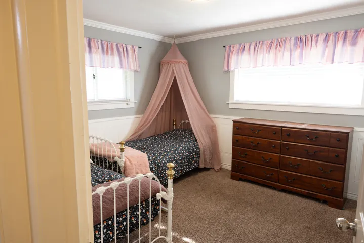 Carpeted room with a two-tone wall treatment featuring white wainscoting and grey paint
