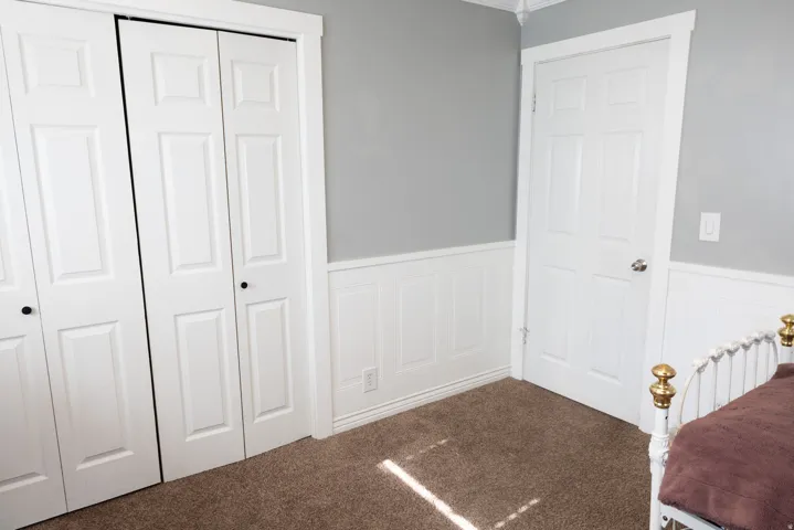 Room featuring light gray walls, white wainscoting, and brown carpet flooring
