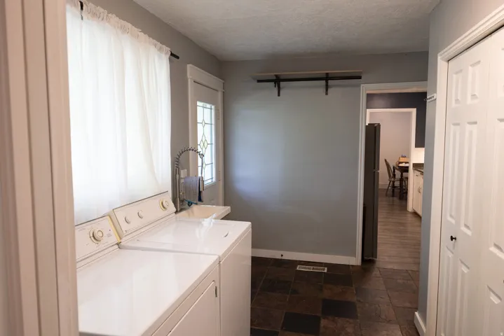 Functional utility space featuring a window, tiled flooring, and a utility sink with a high-arc faucet