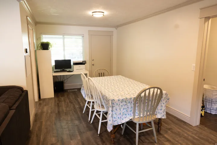 Open dining area featuring wood-finish flooring, white trim, and a window with blinds