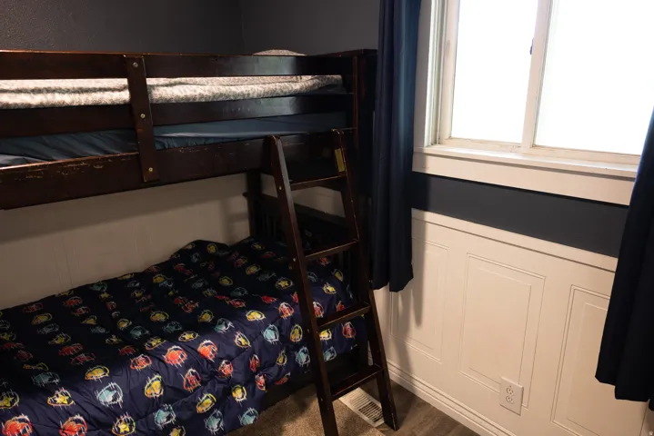 Room featuring white paneling, dark blue walls, a window with white trim, and wood-finish flooring