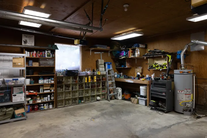 Garage space with concrete flooring, wood paneling, and fluorescent overhead lighting