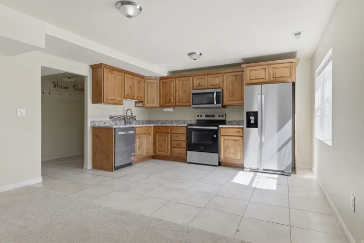 Kitchen featuring light wood cabinetry, granite countertops, tile flooring, and stainless steel appliances