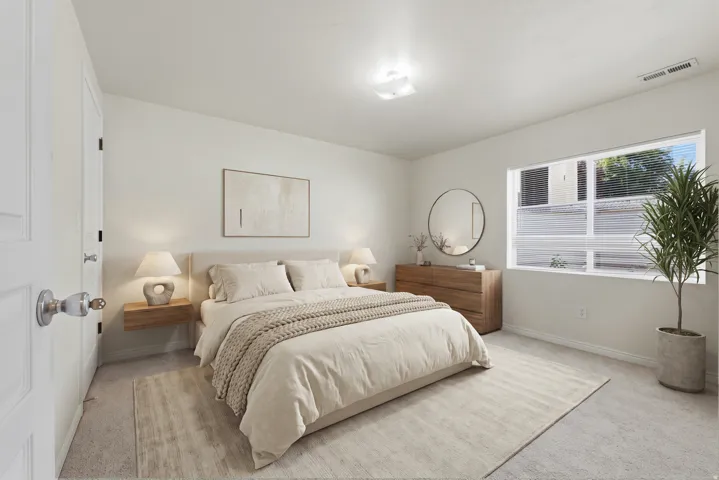 Bedroom featuring light-colored carpeting, white walls, and a large window with horizontal blinds