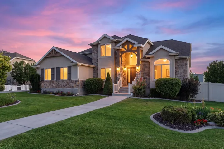 Stucco and stone exterior featuring an inviting covered entry with exposed beam accents