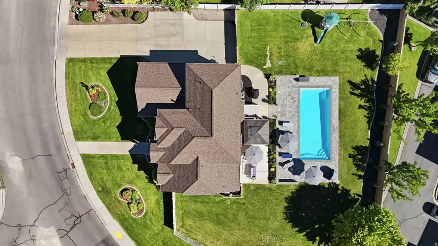 Residential property with a multi-gabled shingle roof, a rectangular in-ground swimming pool, and an extensive paver patio