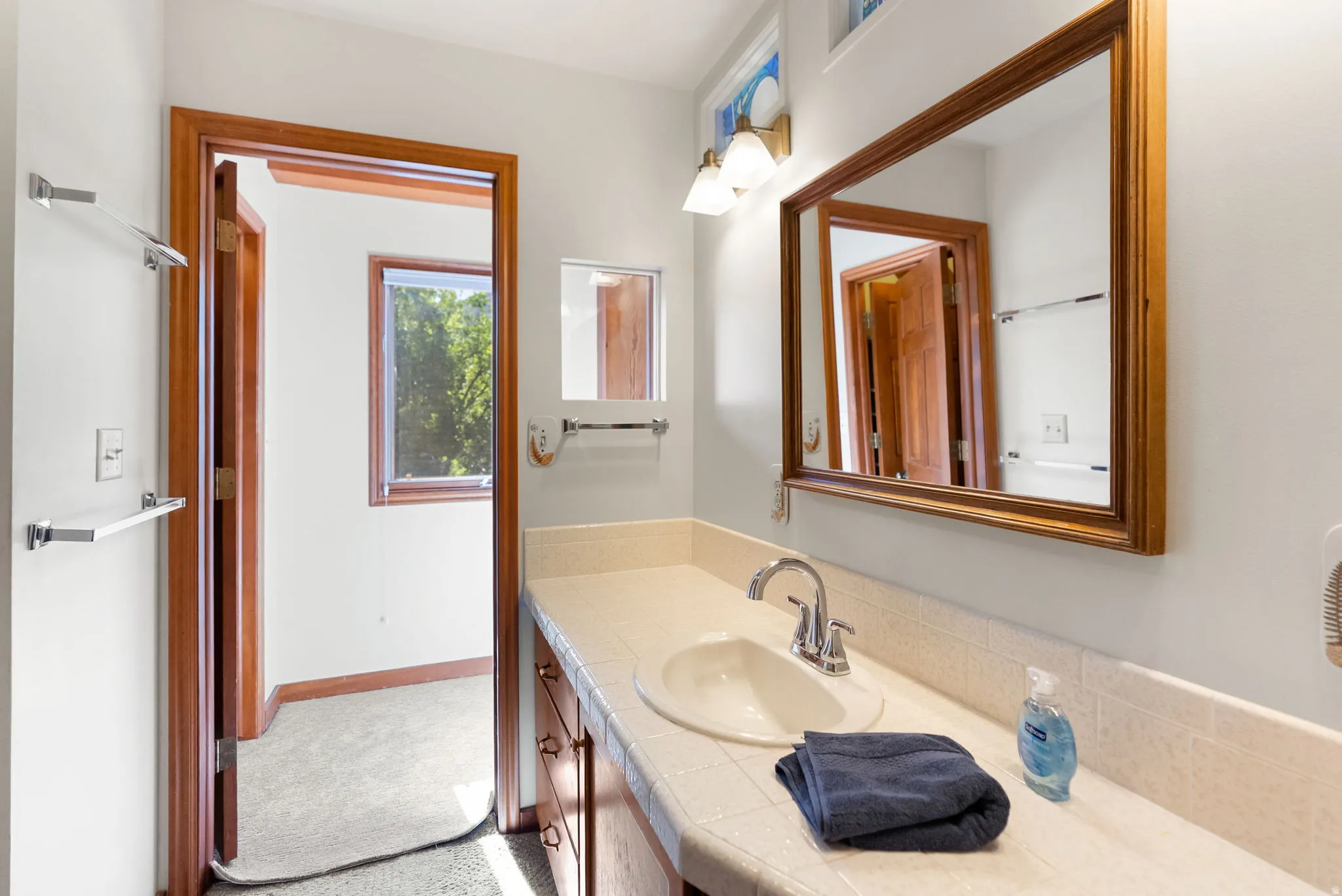 Bathroom vanity featuring an integrated sink, polished chrome faucet, and expansive framed mirror