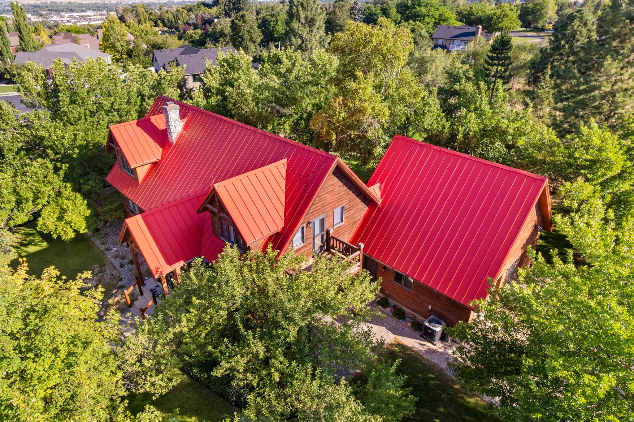 Wood-sided home featuring a prominent red metal roof