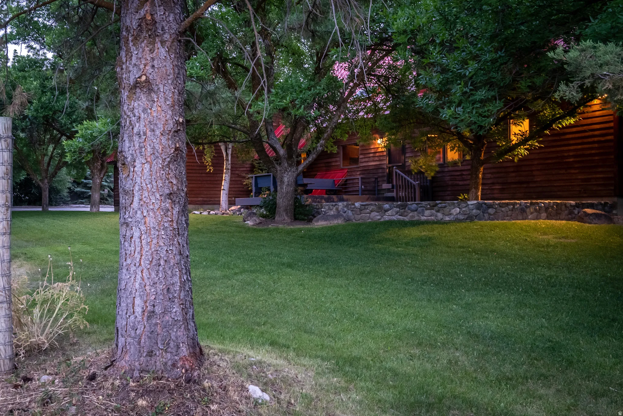 Expansive green lawn with mature trees and a stone retaining wall