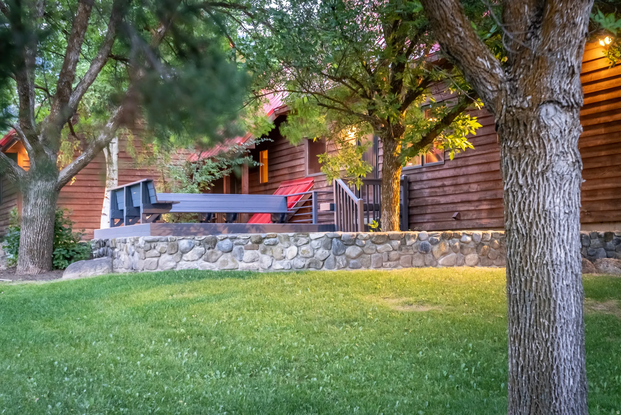 Wood-clad exterior with a red roofline and a stone retaining wall