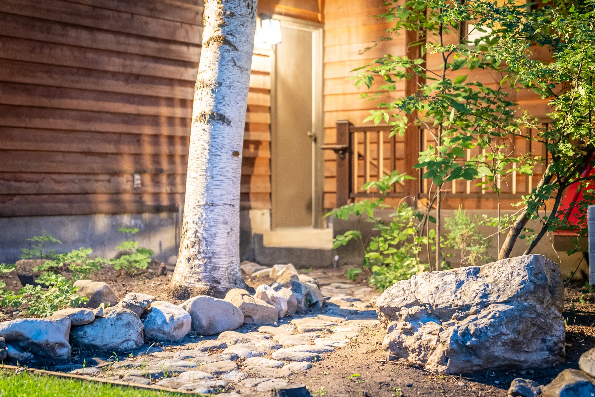 Cobblestone pathway leading to an entry door on a wood-sided structure
