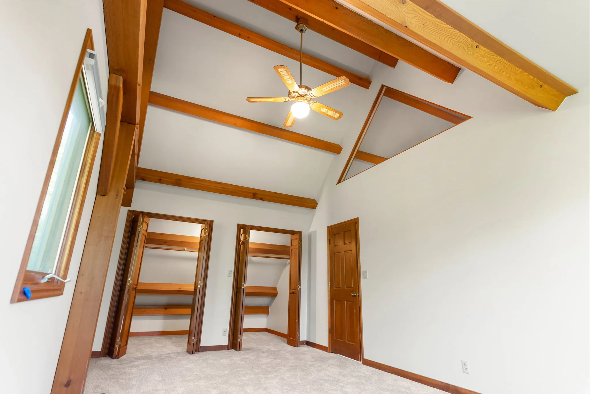 Vaulted ceiling featuring exposed wood beams and a ceiling fan