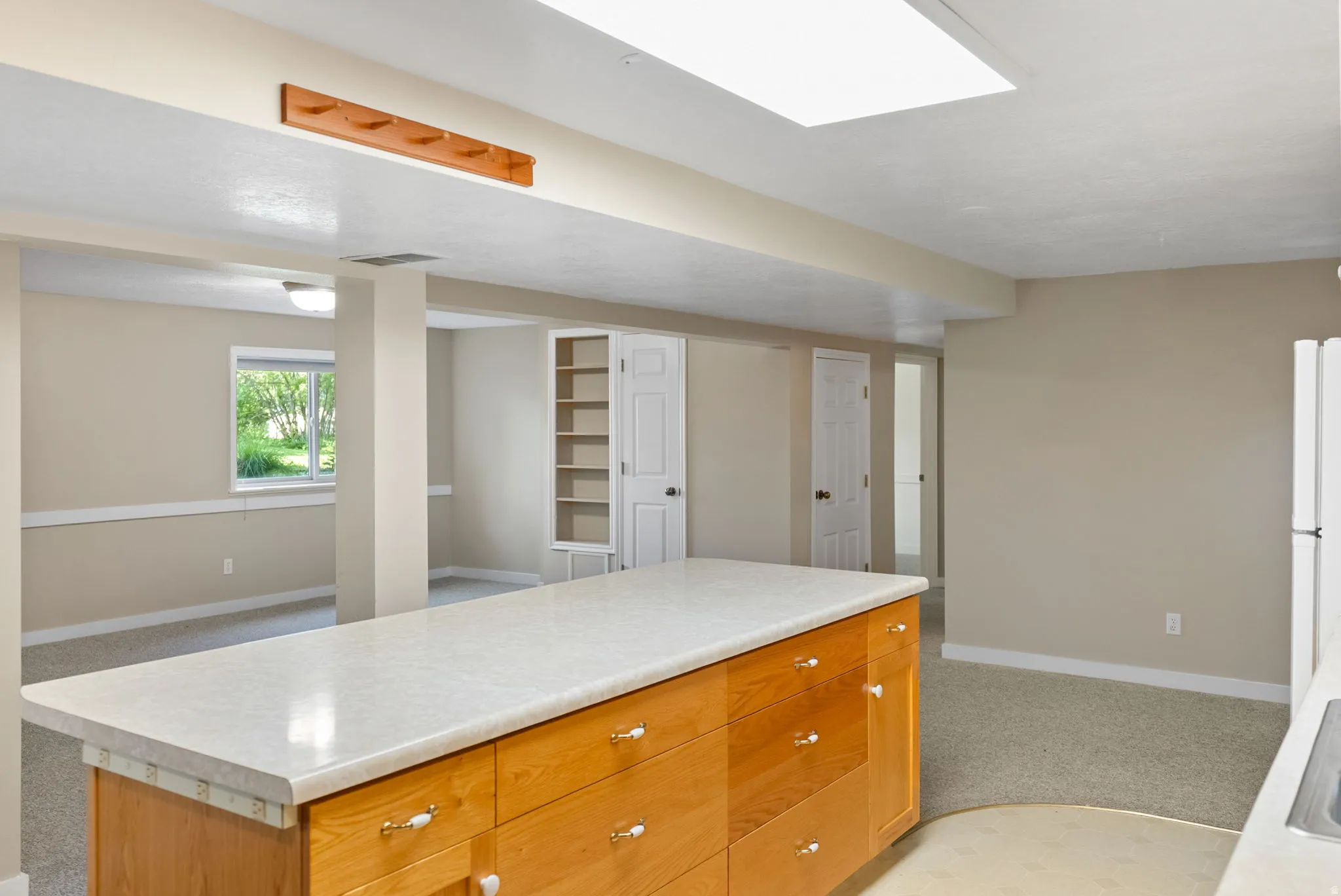 Spacious finished basement featuring a large central island with a light-toned countertop and wood-finish cabinetry