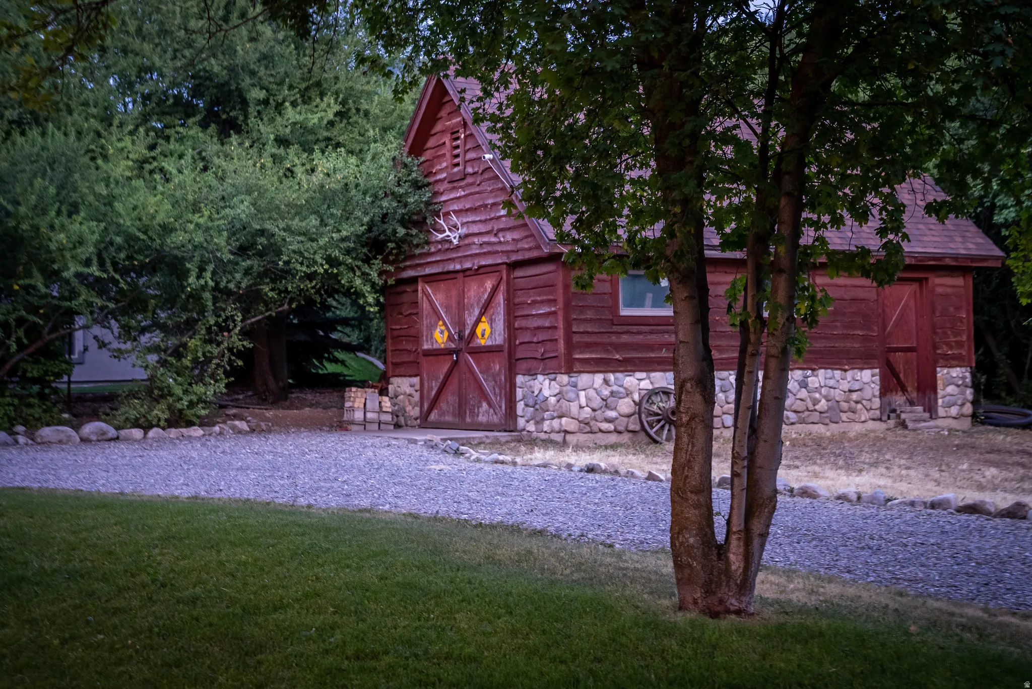 Rustic outbuilding featuring vertical wood siding, a gable roof, and a stone foundation