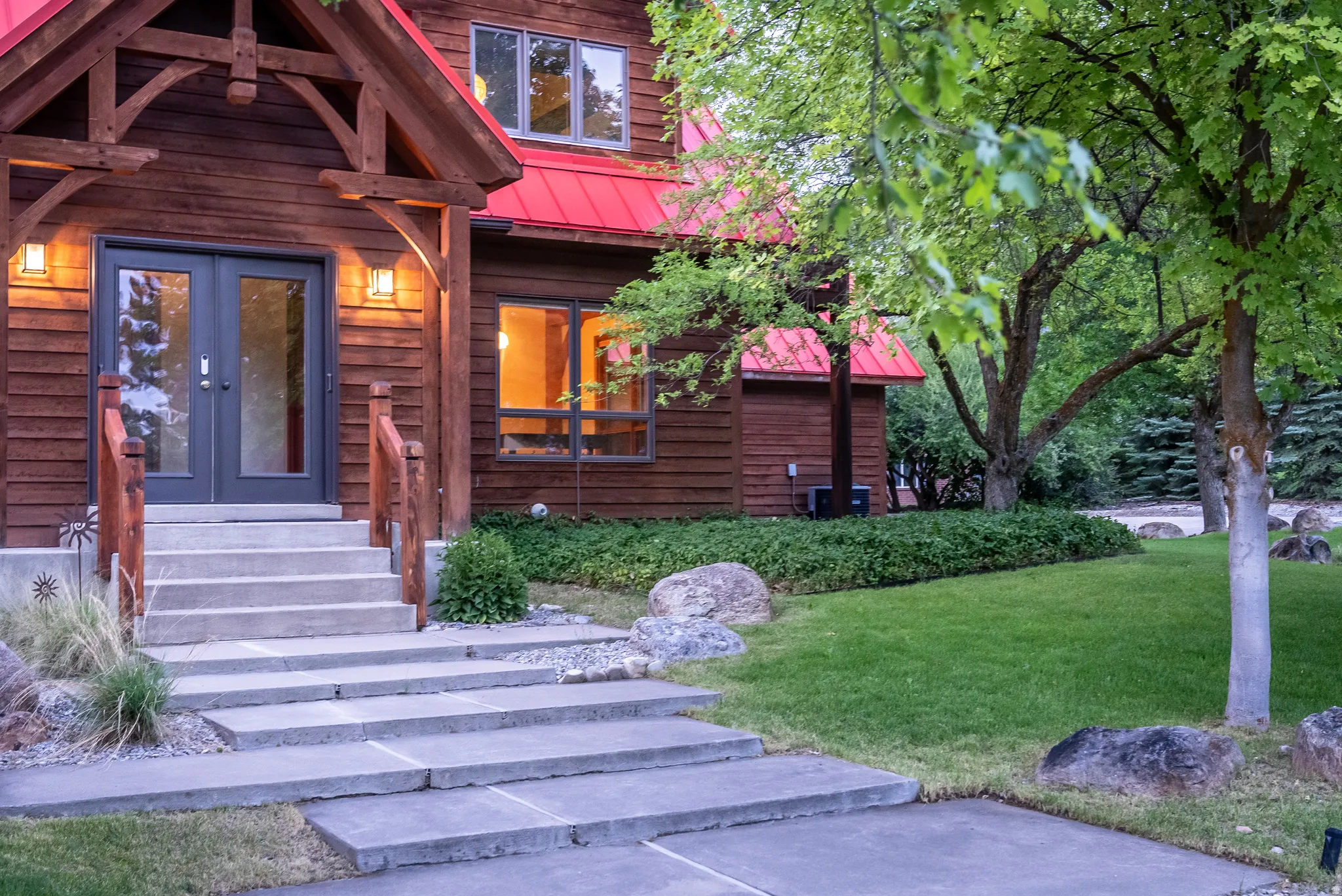 Wood-sided residence featuring a red metal roof and natural wood accents