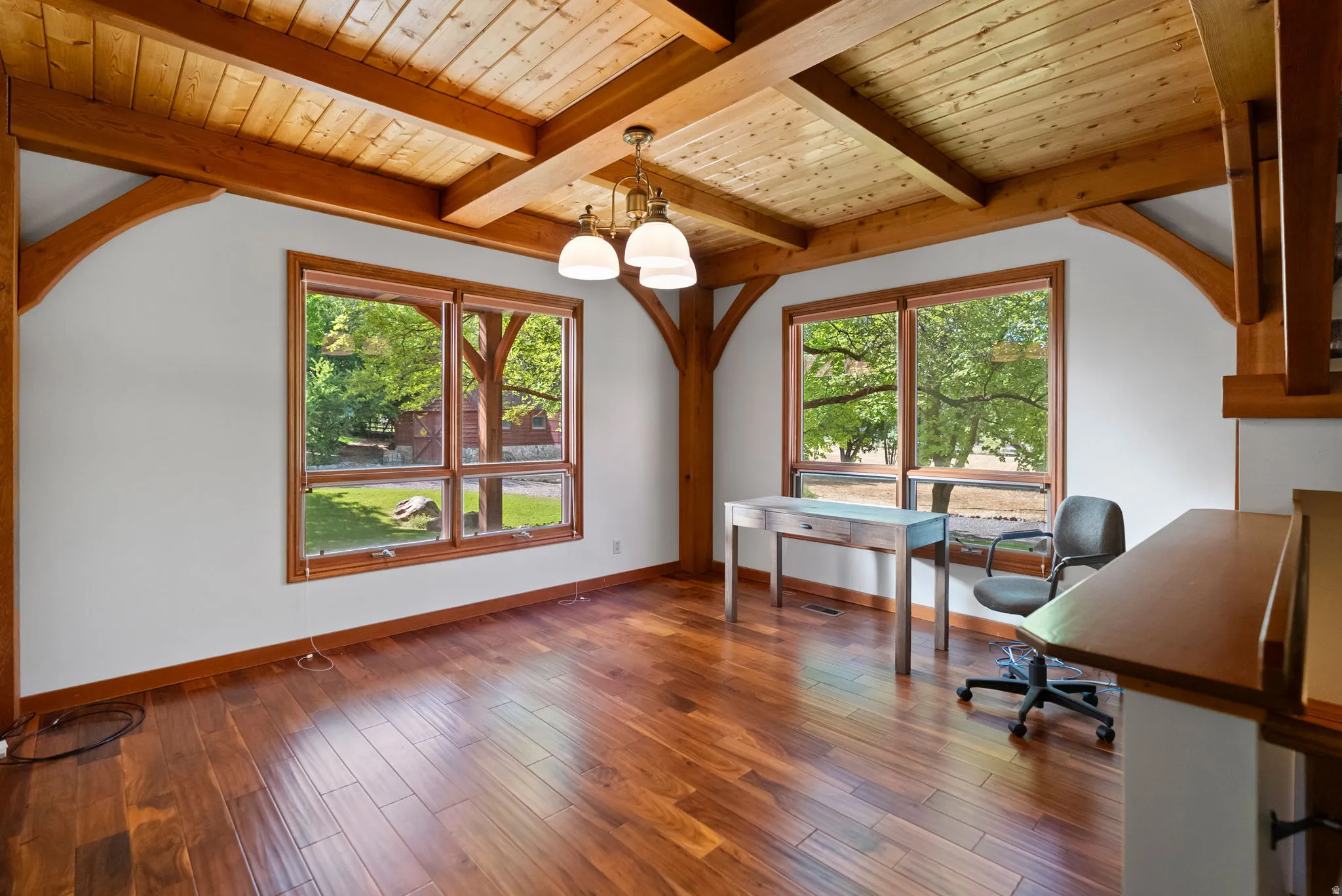 Spacious interior featuring exposed timber beams, wood-finish flooring, and large windows