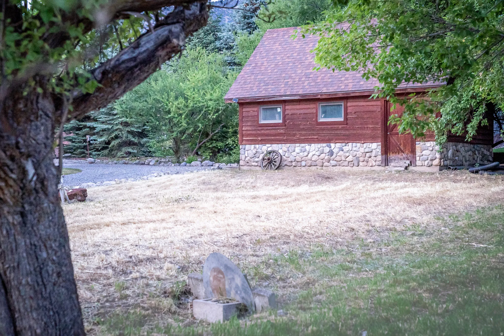 Wood-sided outbuilding featuring a stone foundation and a shingle roof