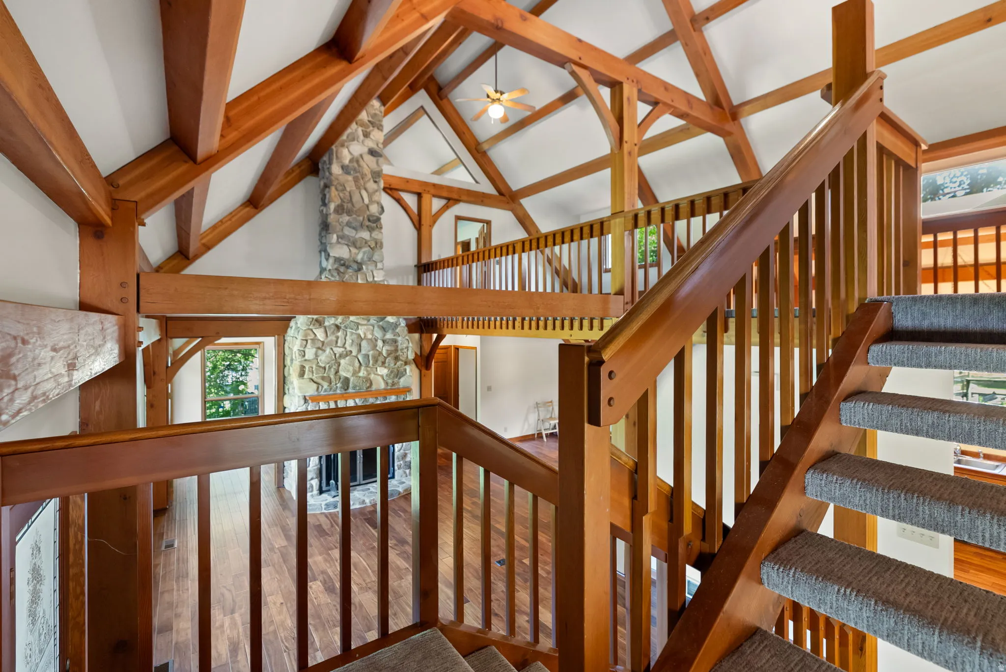 Vaulted ceilings with exposed timber beams define this interior, featuring a stone fireplace