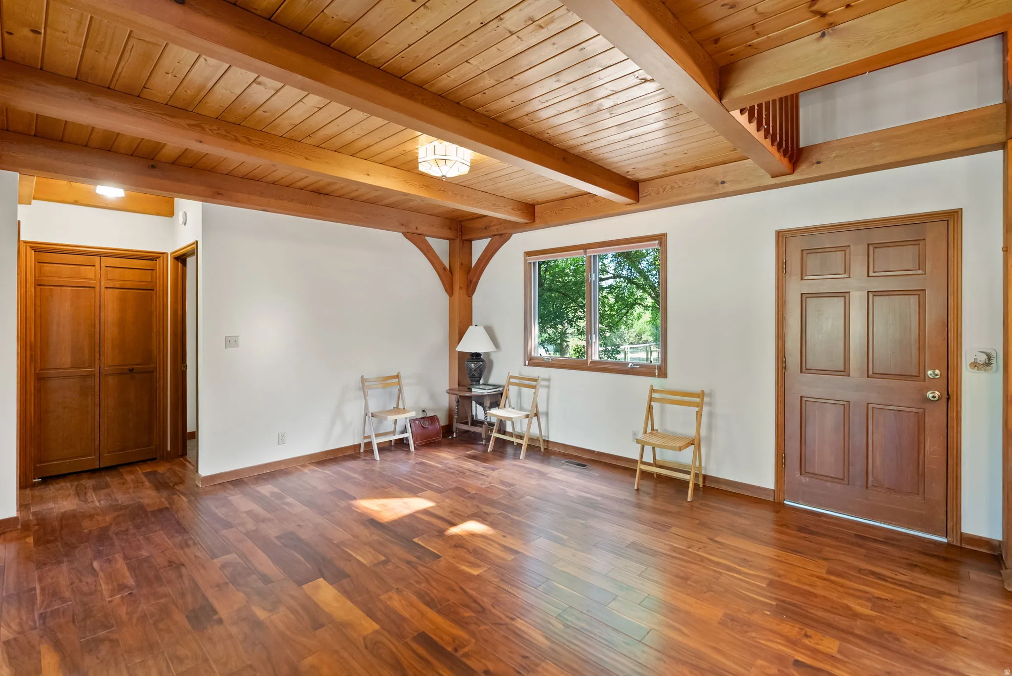 Expansive wood-finish flooring offering a warm ambiance, complemented by exposed wood beams and a paneled wood ceiling