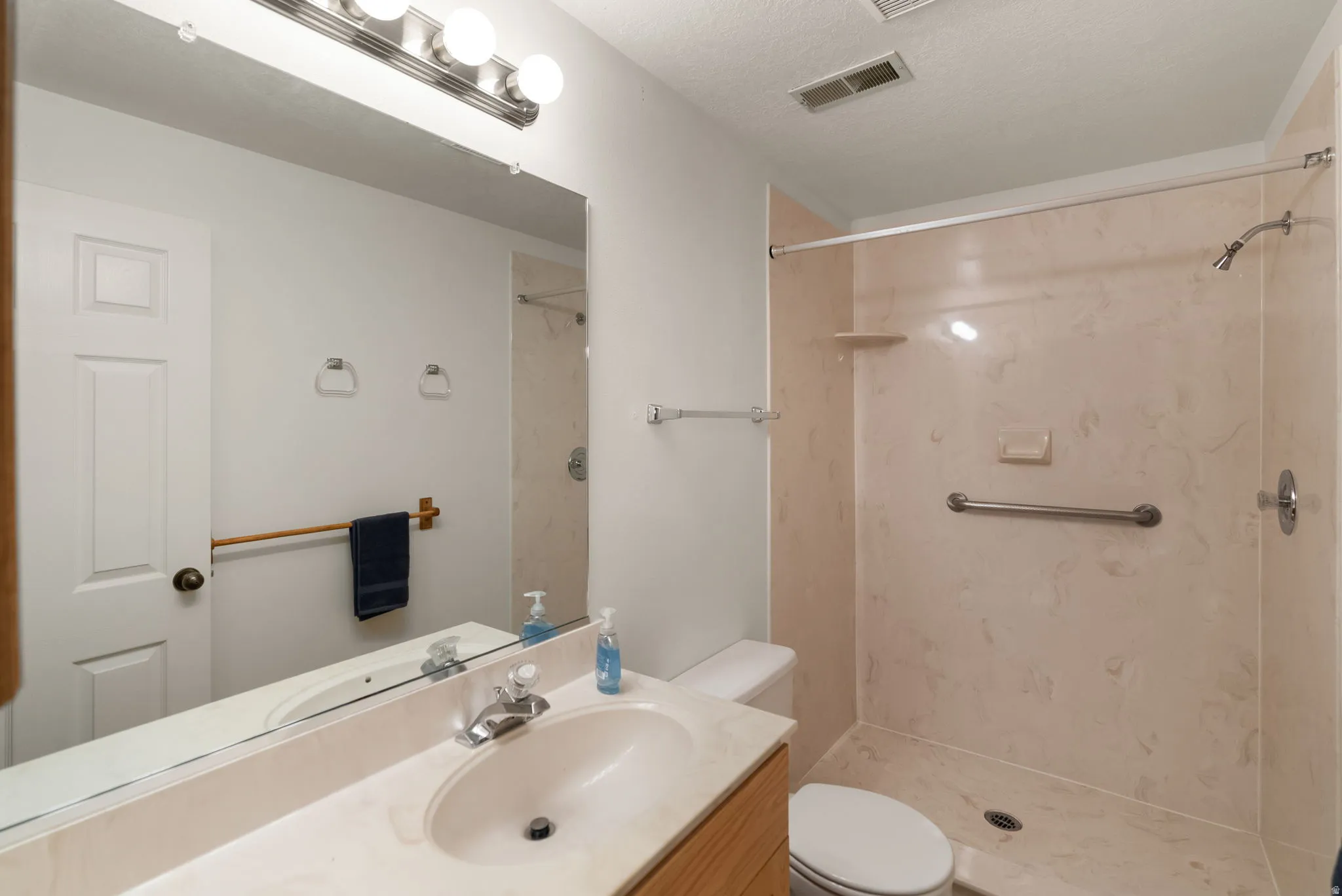 Full bathroom featuring a shower with light-toned paneling and a grab bar