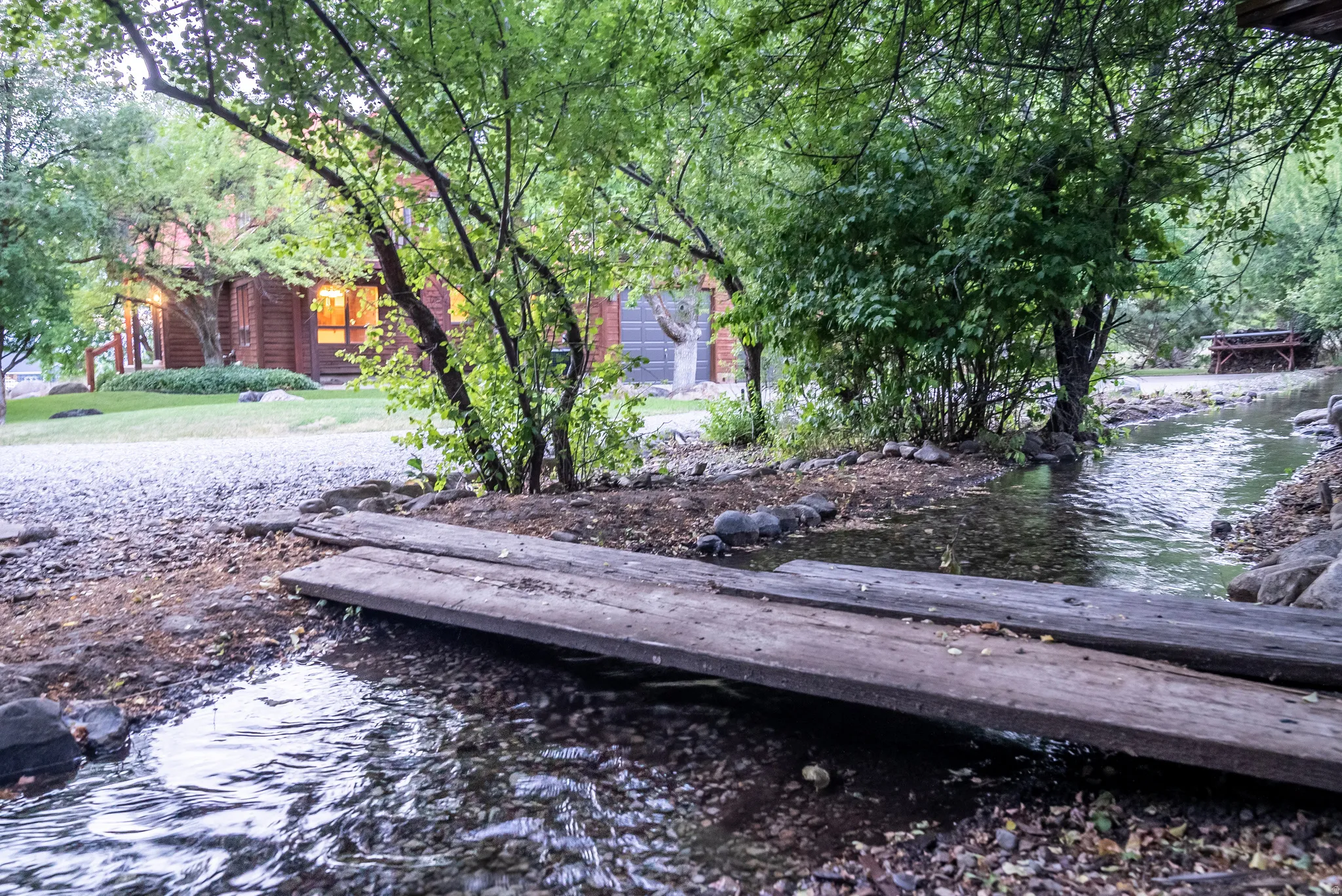 Natural stream with a rustic wood bridge, surrounded by mature trees