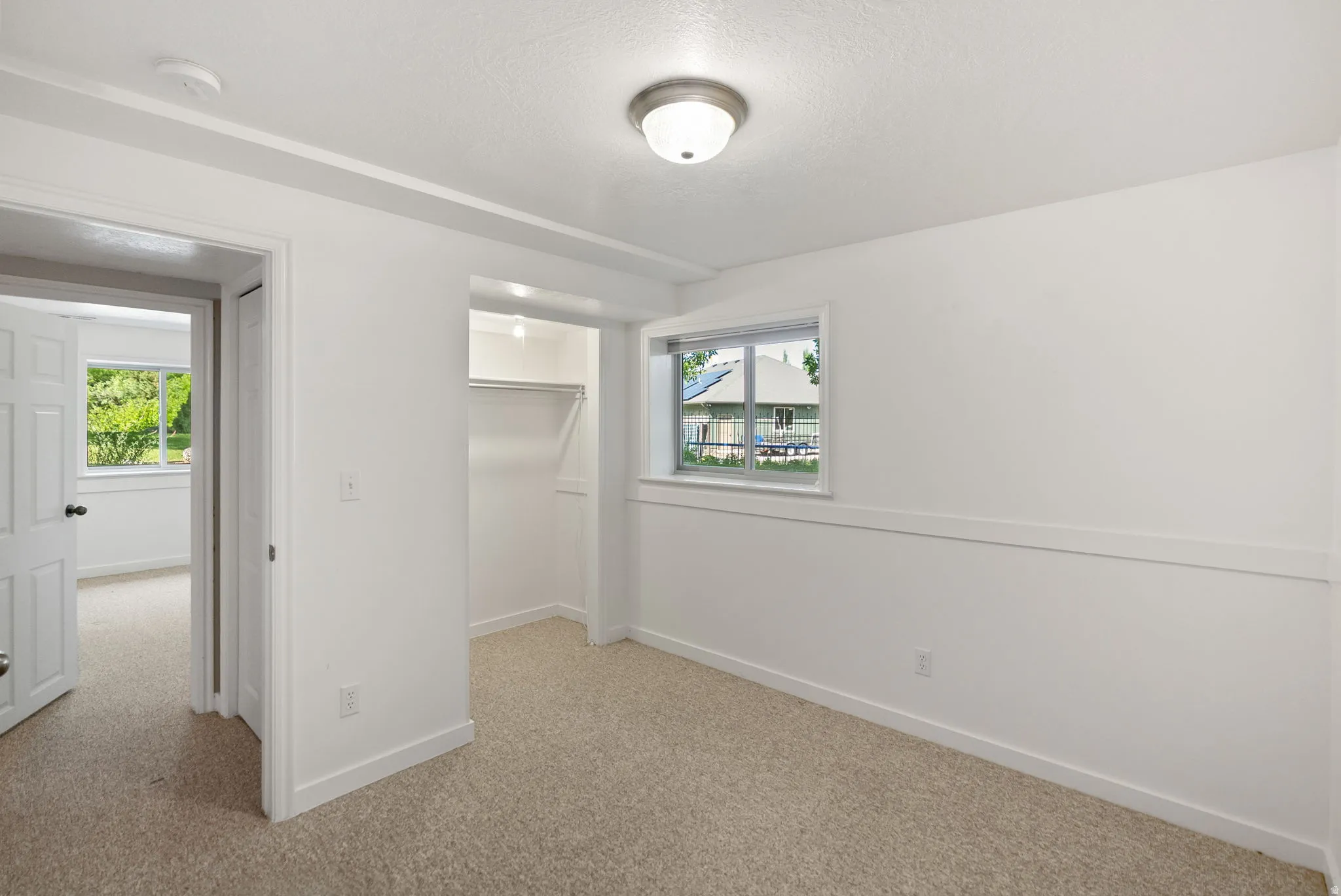 Carpeted room featuring white walls, a single window, a built-in closet with hanging rod, and ceiling-mounted lighting
