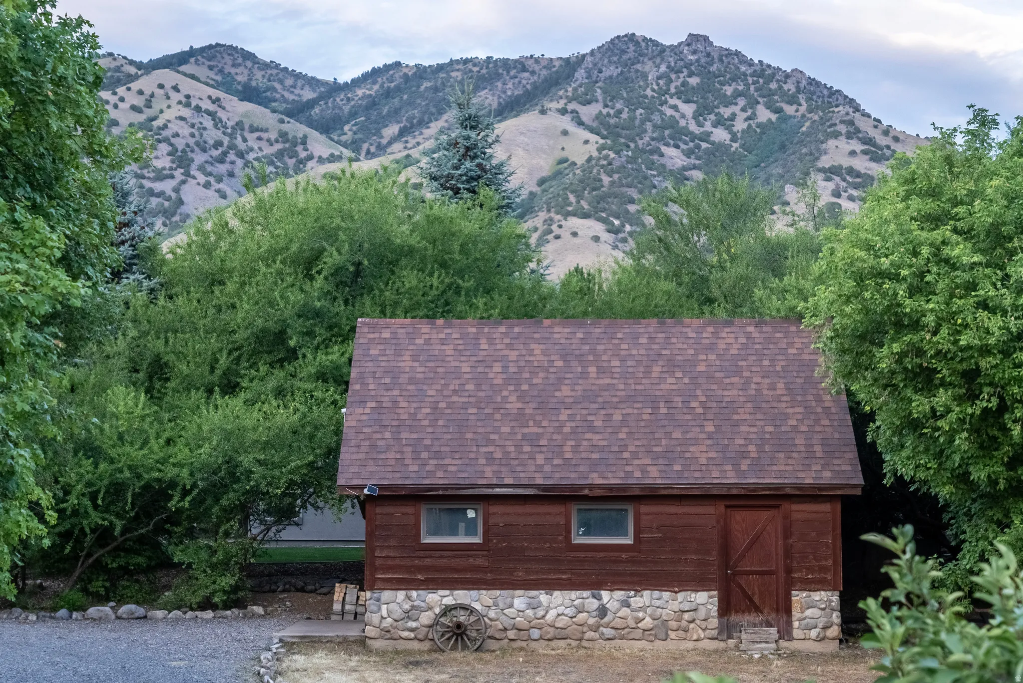 Wood-sided outbuilding with a stone foundation and shingle roof