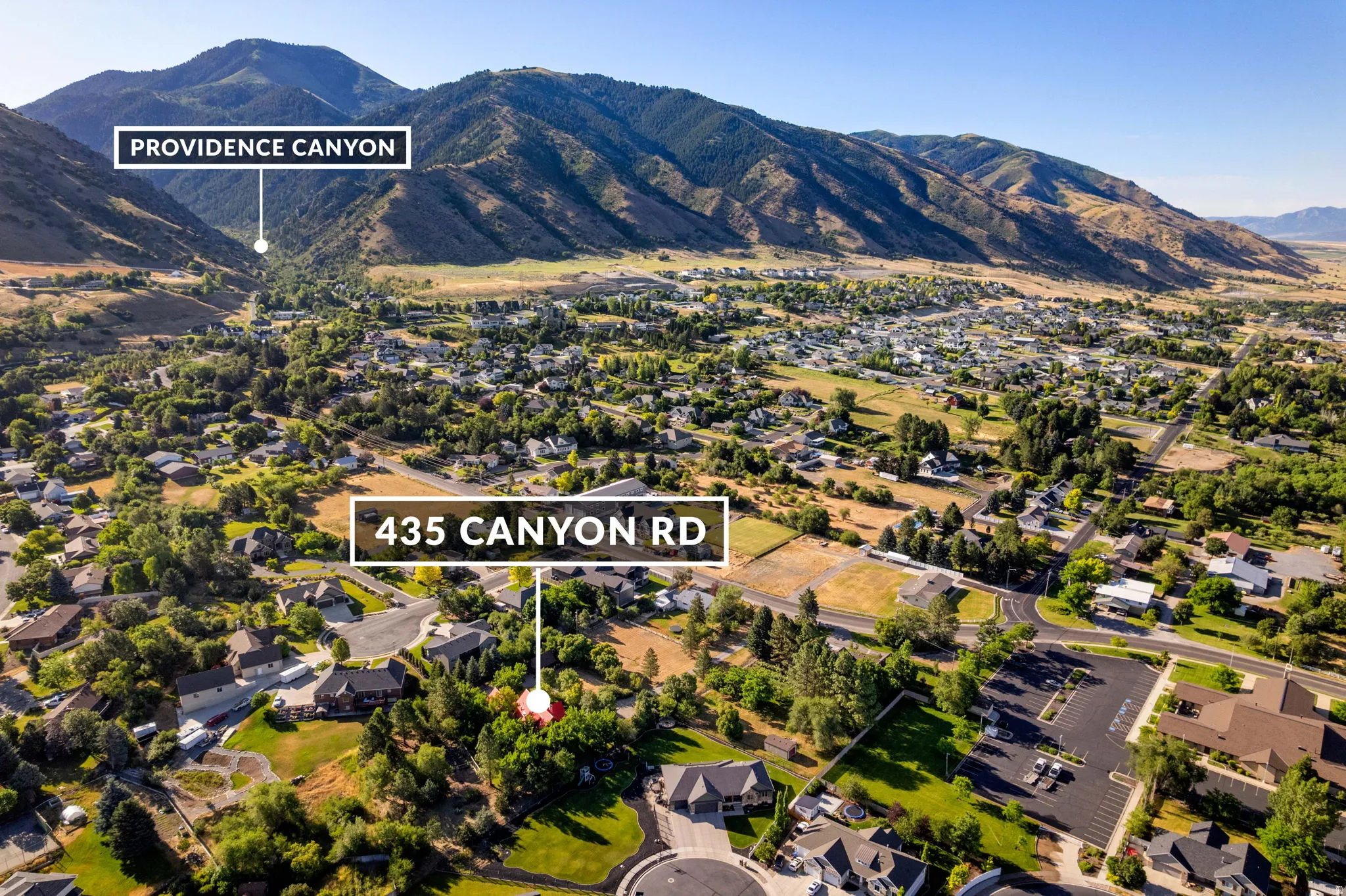 Aerial perspective of a developed residential area with numerous homes, mature trees, and paved roads