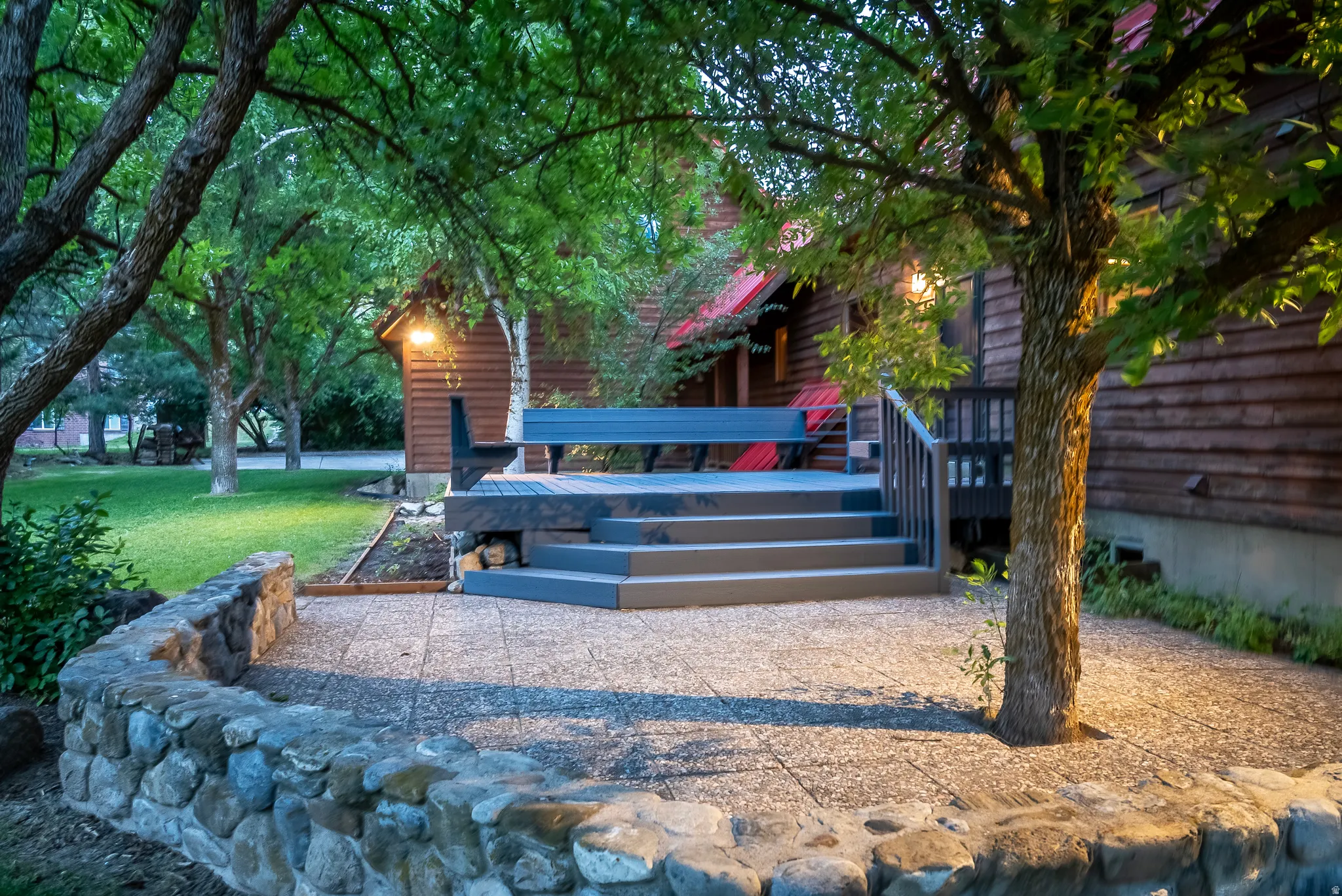 Expansive outdoor patio area featuring a stone retaining wall and a multi-level deck constructed with composite materials