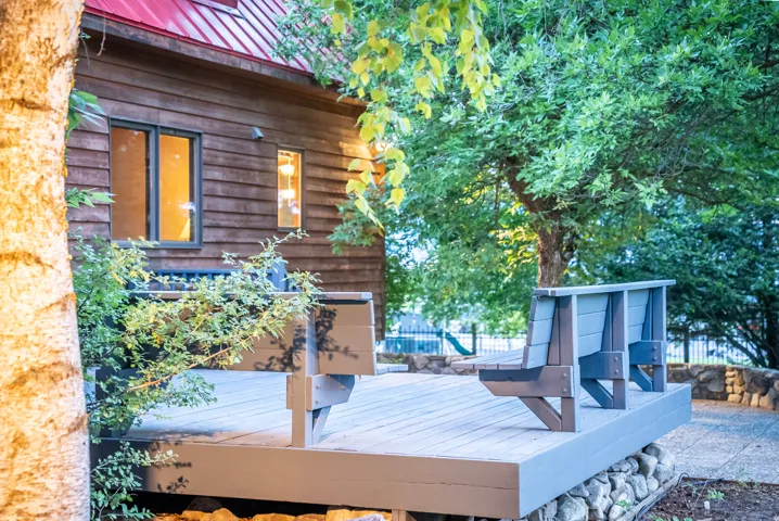 Outdoor deck area featuring built-in seating, a stone retaining wall, and mature landscaping