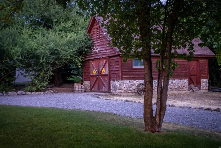 Rustic outbuilding featuring vertical wood siding, a gable roof, and a stone foundation