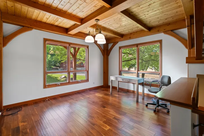 Spacious interior featuring exposed timber beams, wood-finish flooring, and large windows