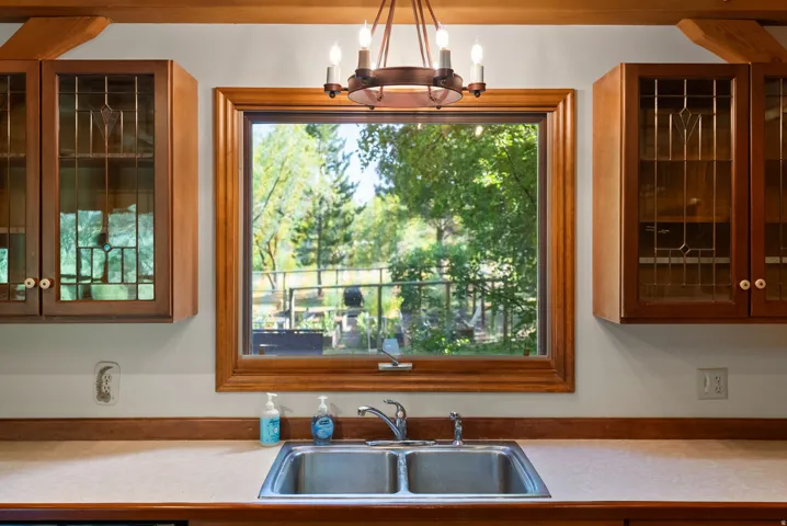 Kitchen window with wood trim, dual-basin stainless steel sink, and light-colored countertop