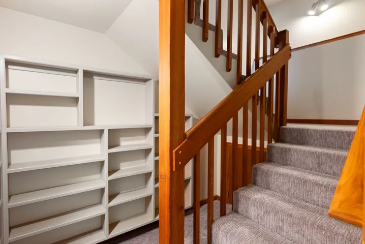 Custom built-in shelving and a carpeted staircase with wood railings