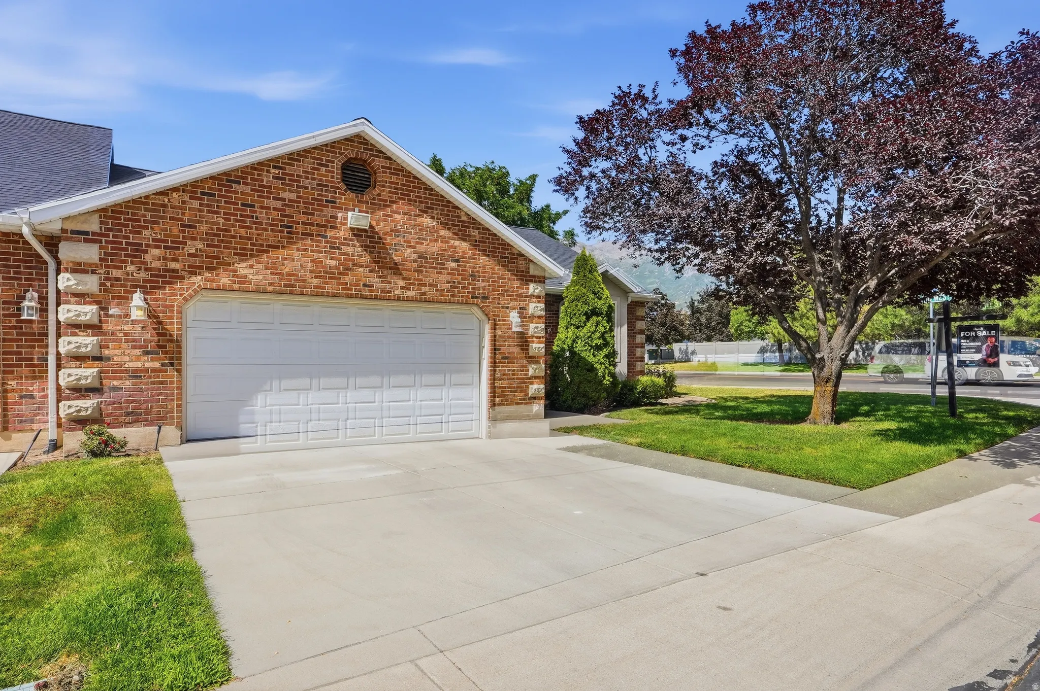 Brick exterior with stone accents, a two-car garage, and a concrete driveway