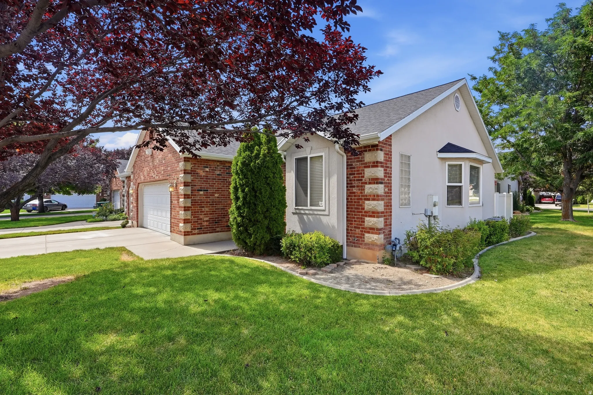Exterior featuring brick and stucco siding, an attached garage with a white door, and a bay window