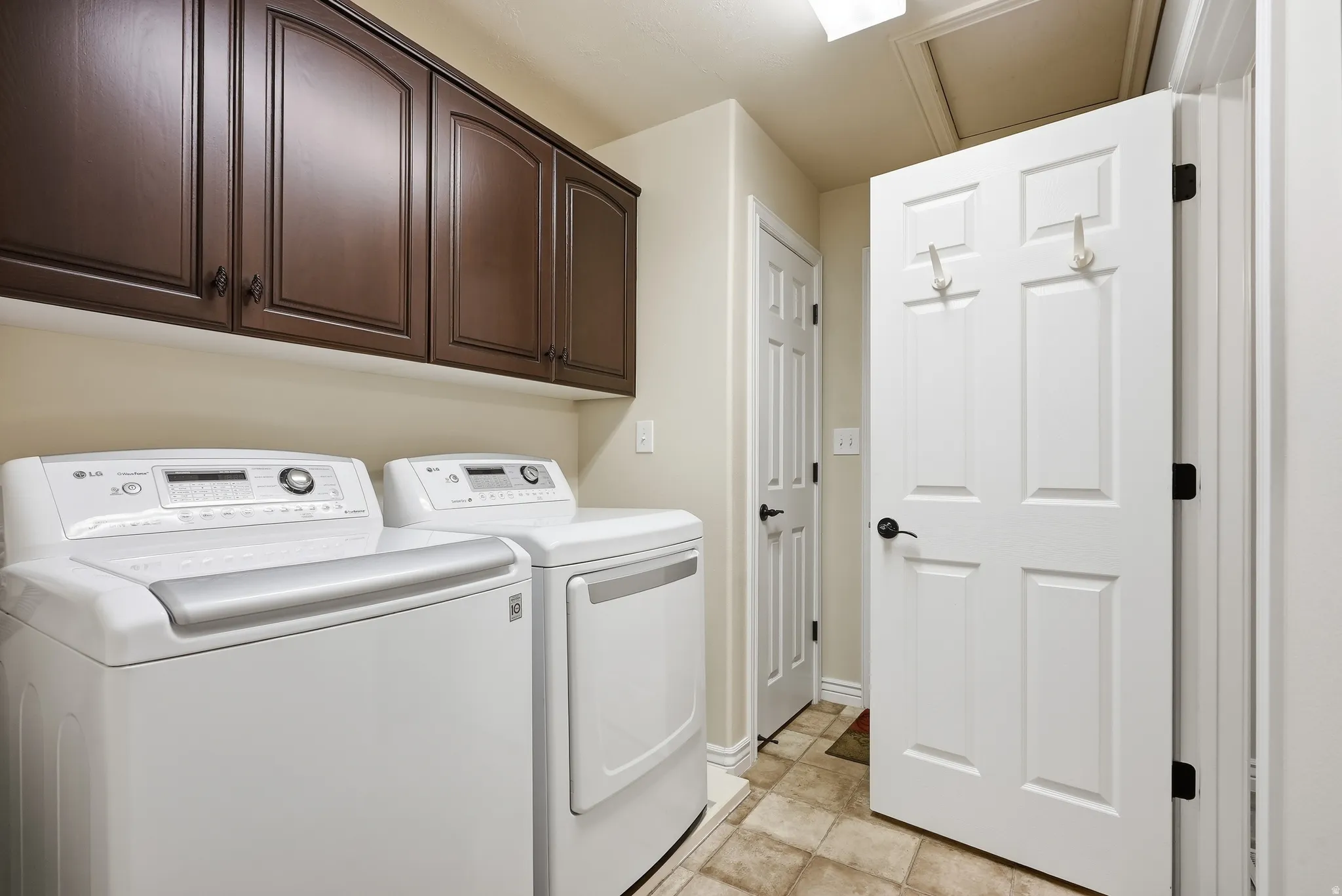 Laundry area featuring dark wood-finish cabinetry, neutral wall paint, and tiled flooring
