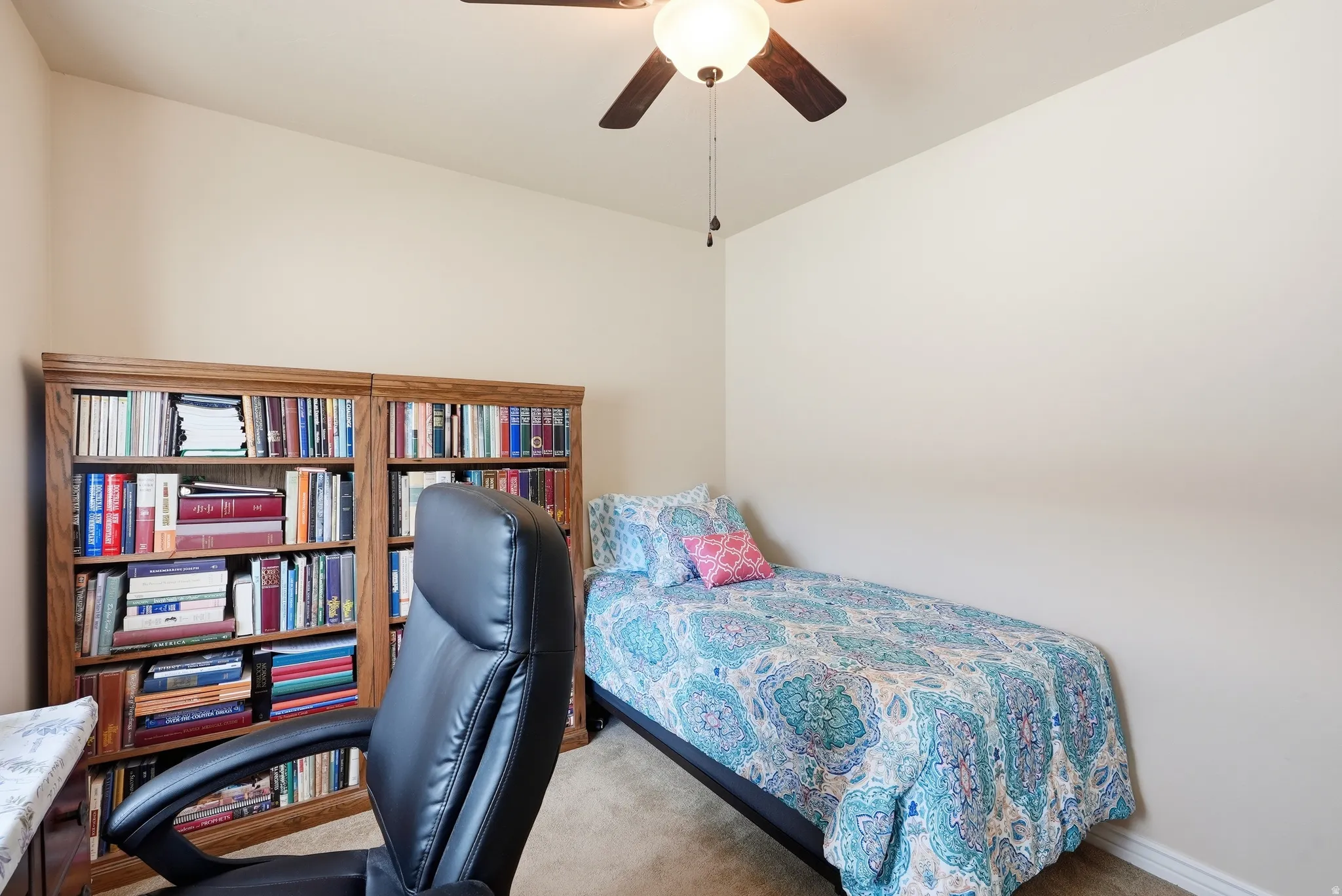 Room featuring built-in wood bookcases, neutral wall tones, and a ceiling fan with integrated lighting