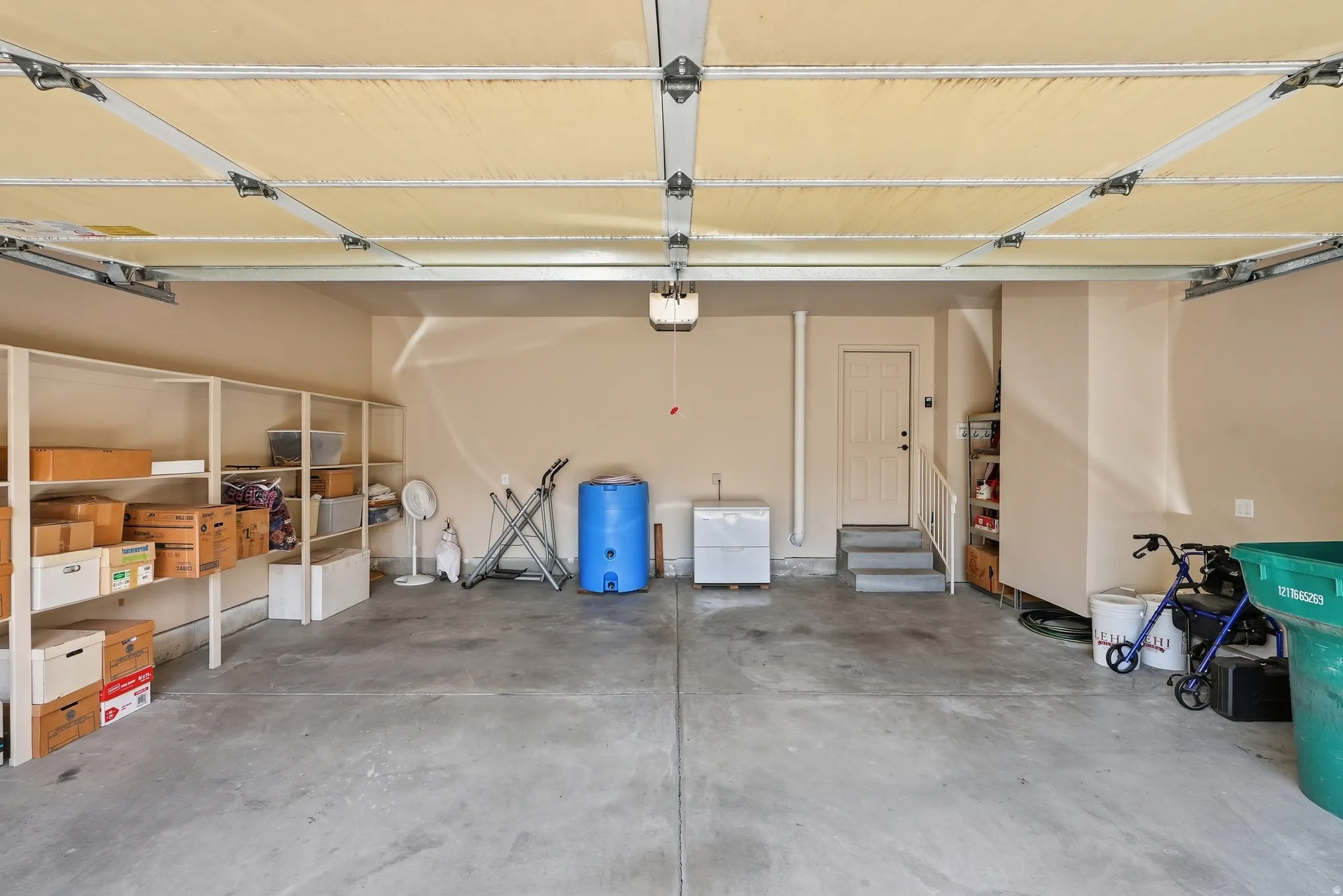 Spacious garage featuring concrete flooring, built-in shelving, an overhead door with opener, and interior access door