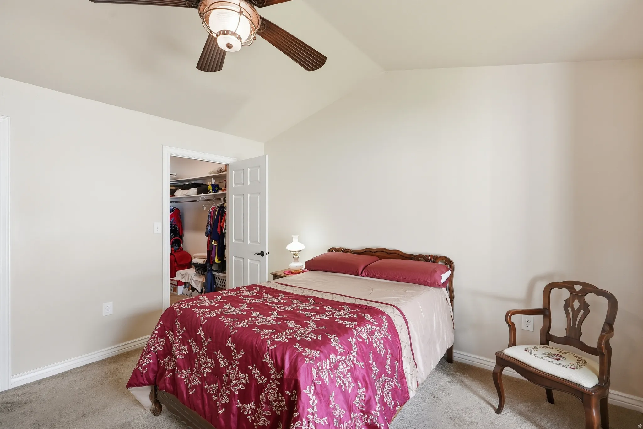 Bedroom featuring vaulted ceilings, neutral wall tones, carpeted flooring, and a built-in closet with shelving and hanging rods