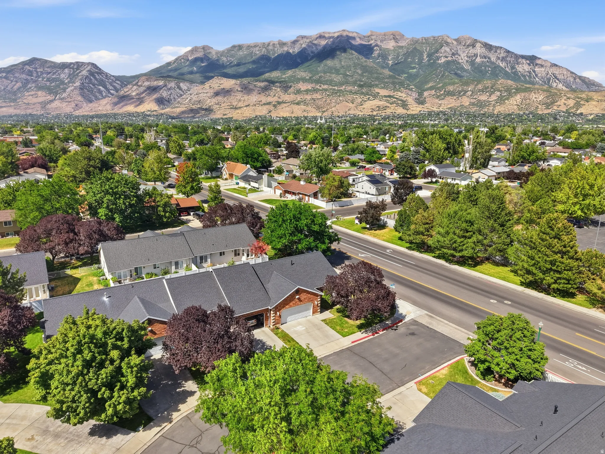 Residential neighborhood with mountain backdrop featuring mature trees, paved streets, and a variety of home styles