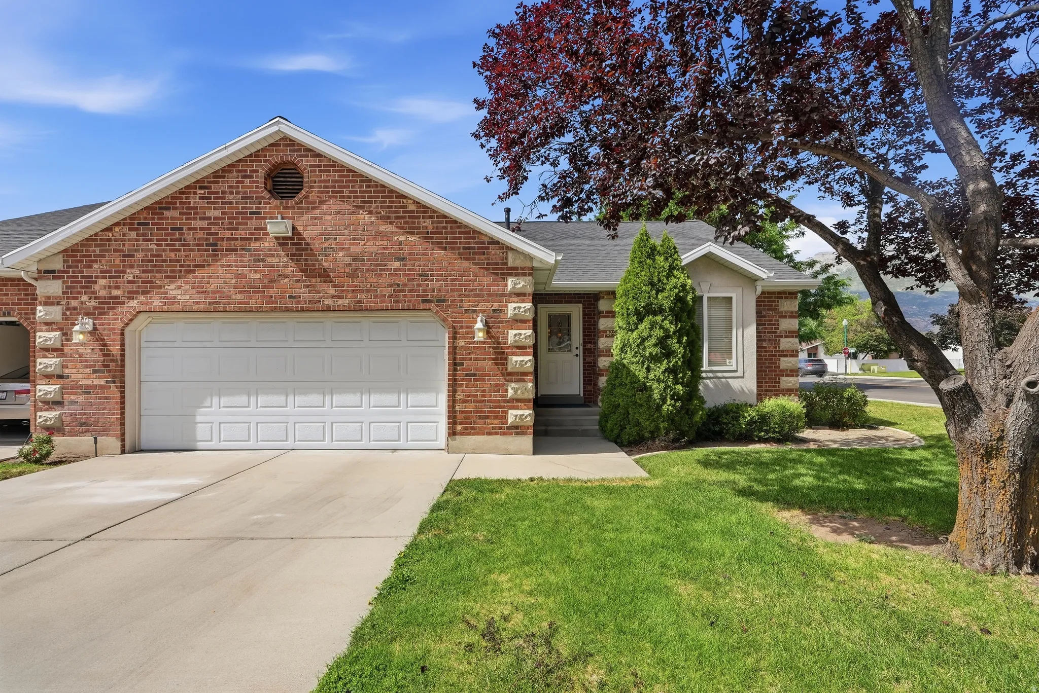Brick exterior featuring a two-car garage, concrete driveway, and front lawn
