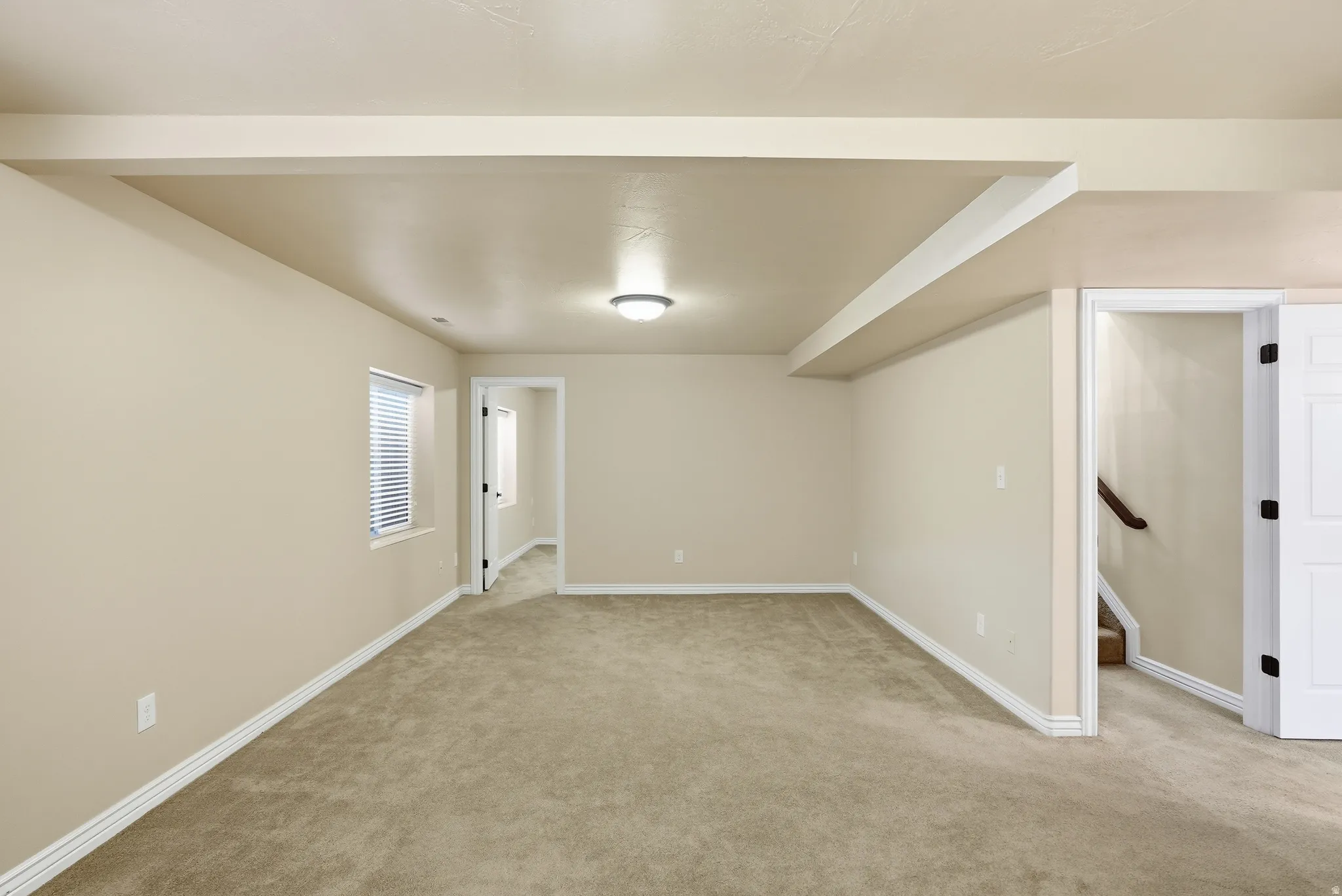 Expansive carpeted area with neutral wall tones and white baseboards