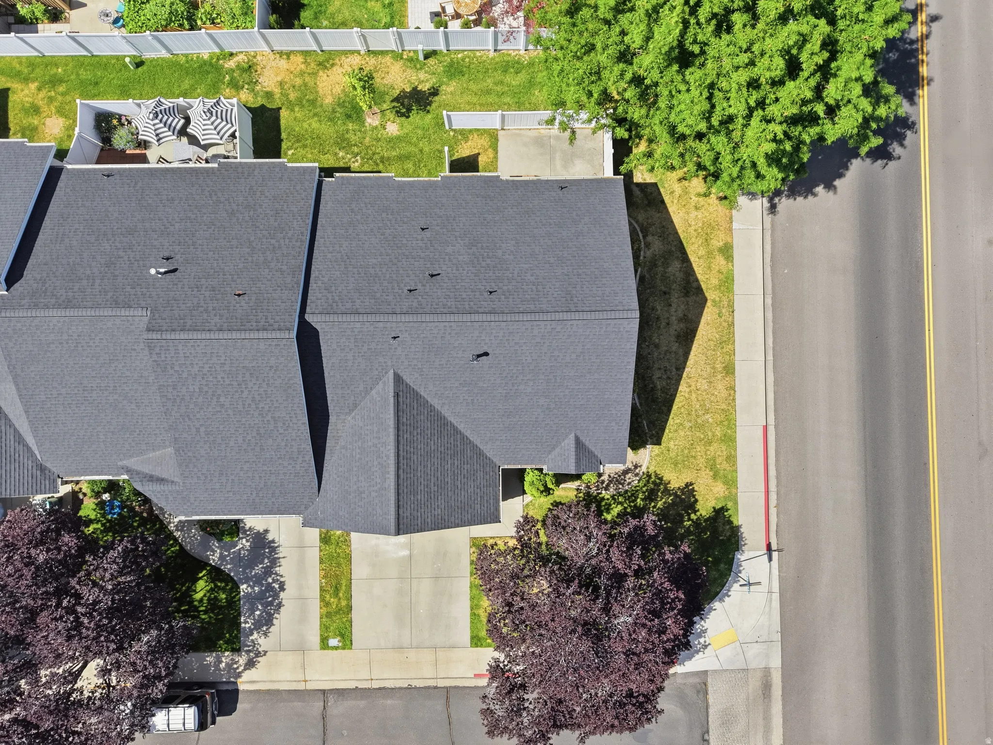 Aerial perspective showcasing the property's dark gray shingle roof, paved driveway, and established front landscaping