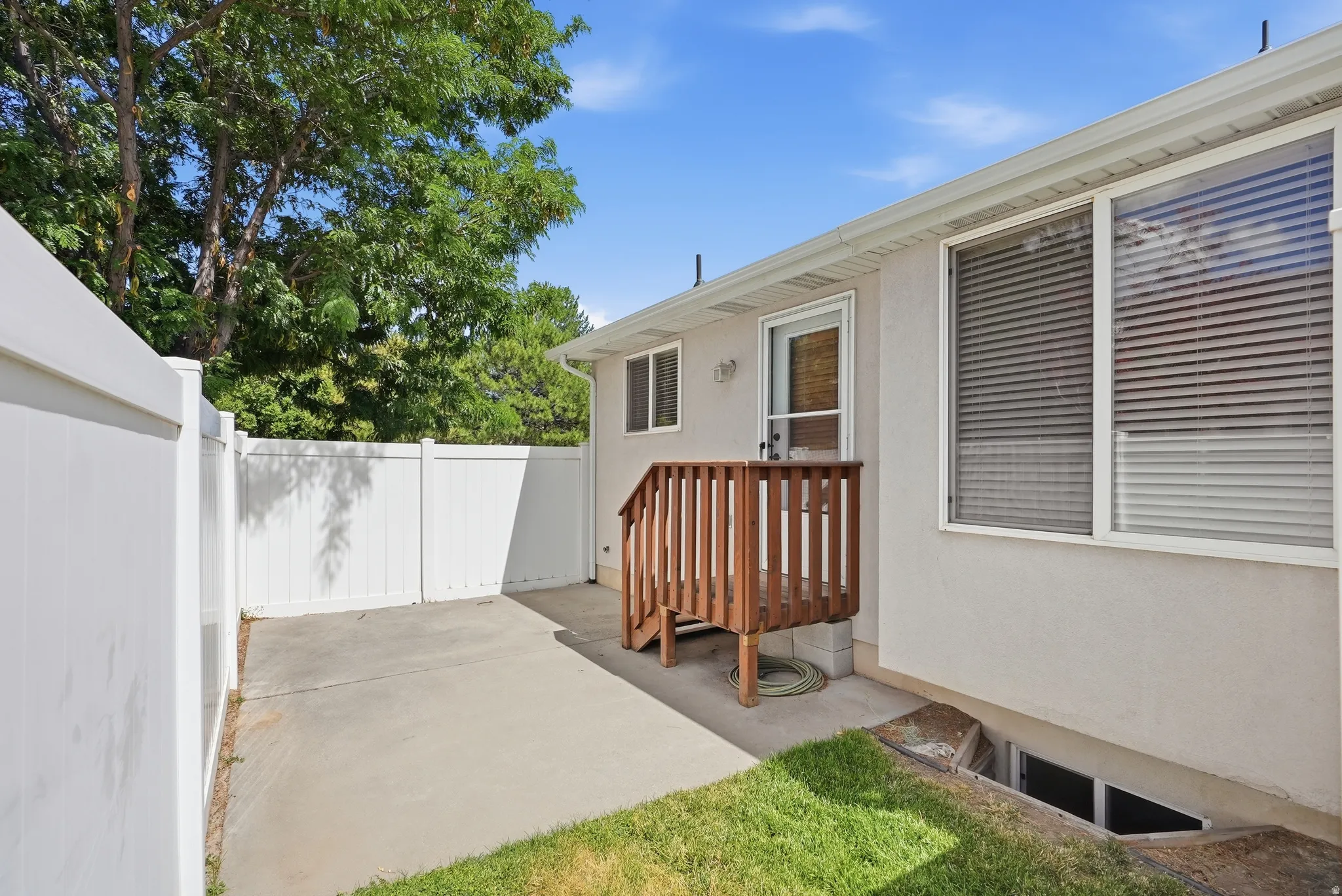 Private patio space featuring concrete surfacing and a white vinyl privacy fence
